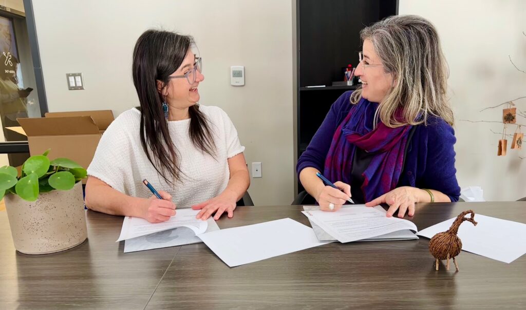 Julie Girard et Nathalie Guay signent leur entente en se souriant mutuellement.